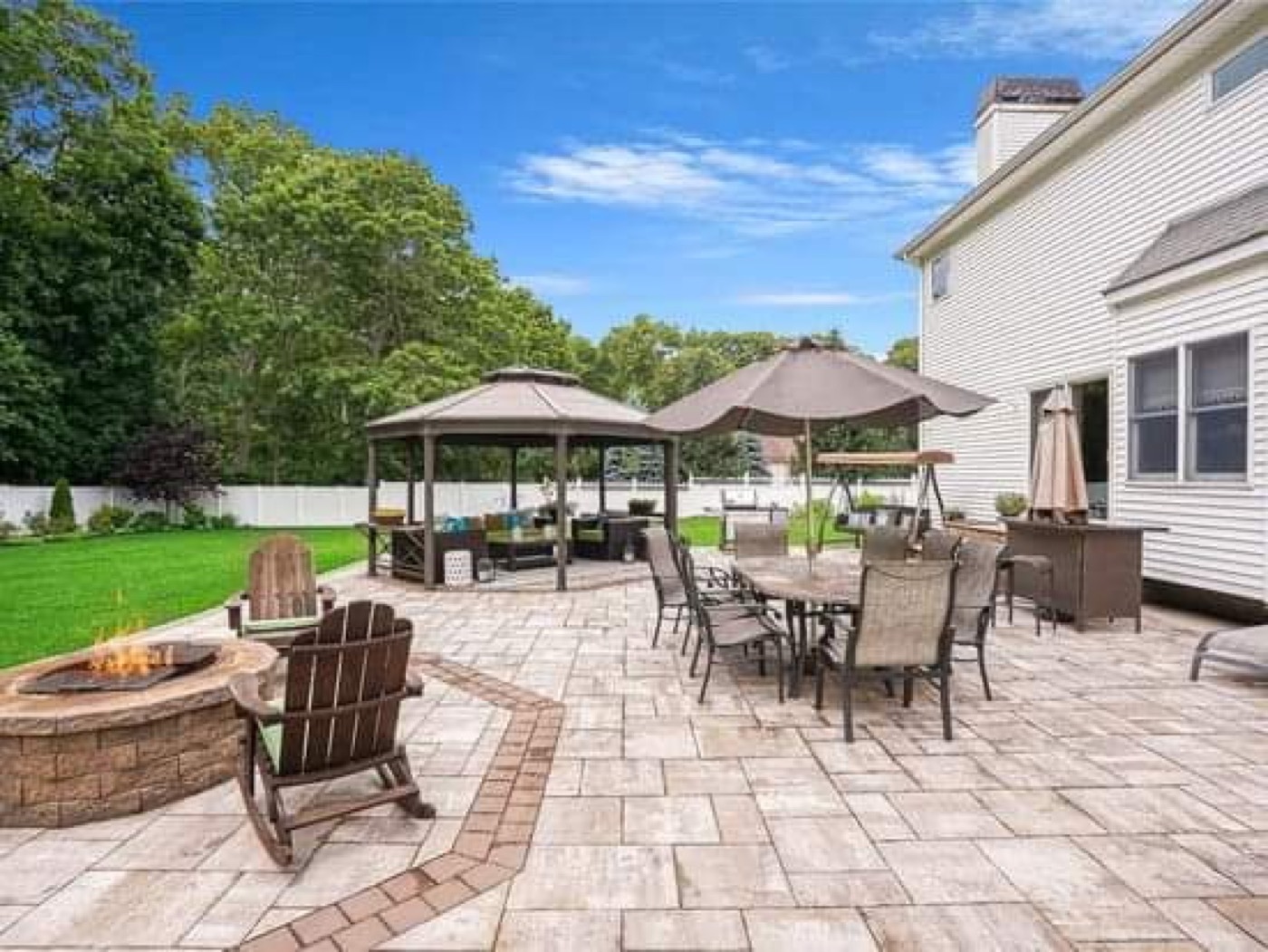 Completed backyard paver patio with fire pit and outdoor seating zones