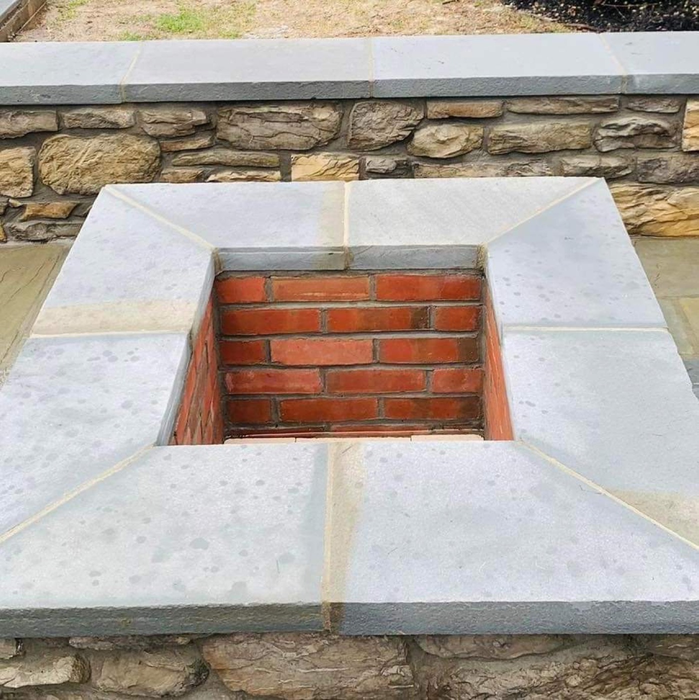 Brick fire pit with stone cap and stone wall