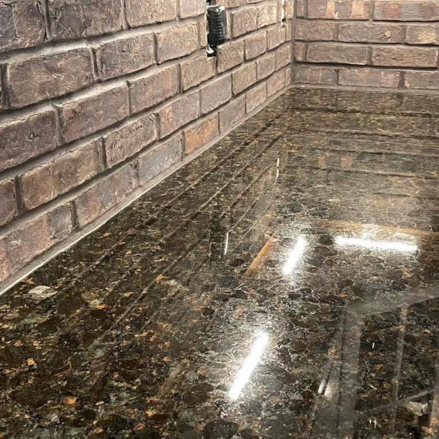 Polished granite counter detail against brick wall