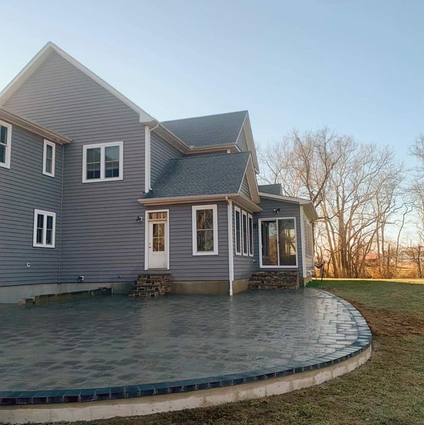 Large curved backyard paver patio with dark edge