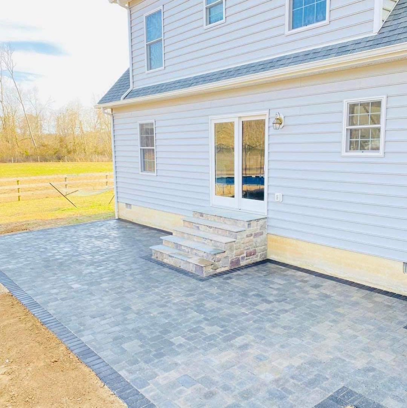 Large gray paver patio with steps and dark border