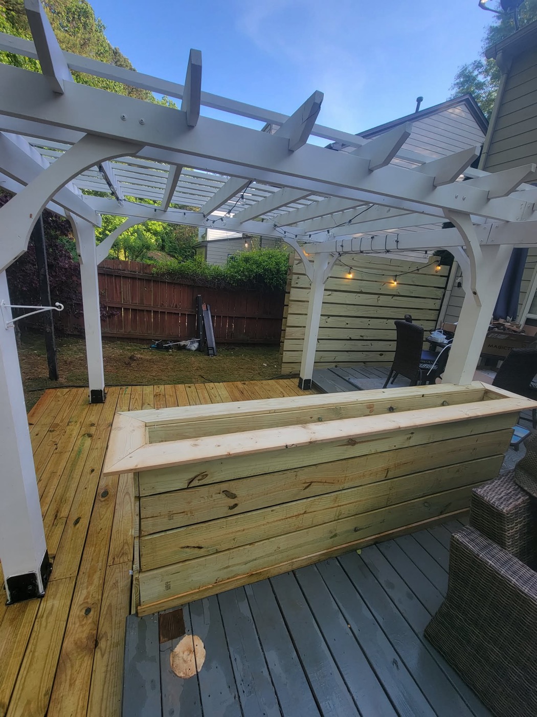 White pergola with wood deck and built-in bench