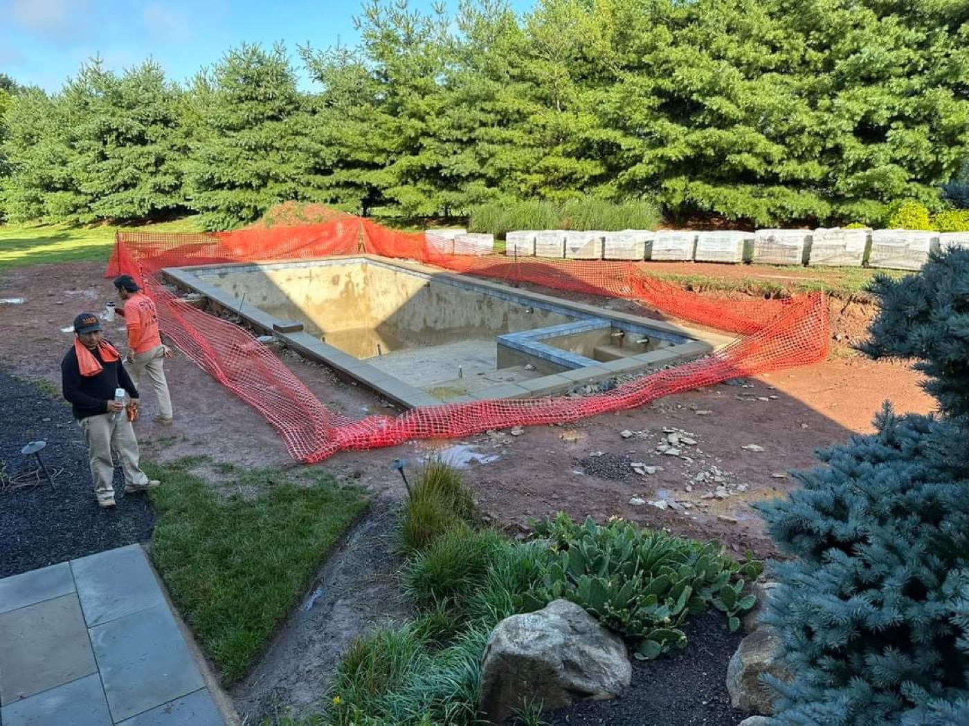 Pool hardscape construction progress with paver materials staged